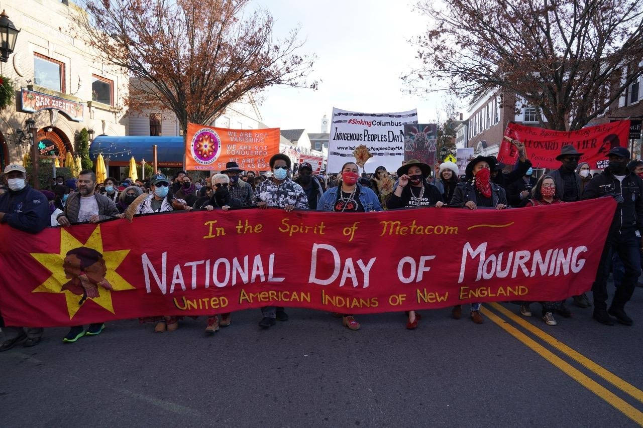 Native Americans carrying National Day of Mourning banner